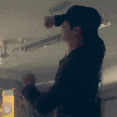 a man in a suit and hat is working on a light fixture