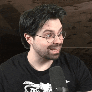 a man wearing glasses and a black shirt is talking into a microphone