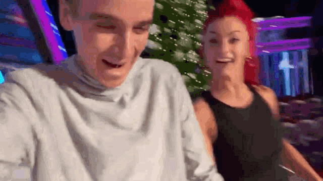 a man and a woman with red hair are standing next to each other and smiling .