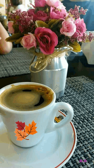 a cup of coffee next to a vase of pink roses
