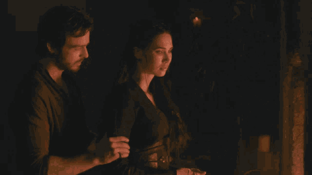 a man and a woman are standing next to each other in front of a fire