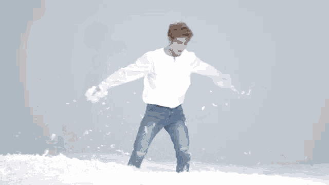 a man in a white shirt and jeans is standing on a pile of feathers .