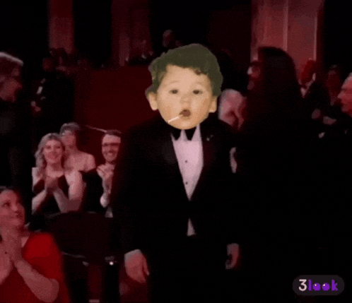 a baby in a tuxedo is smoking a cigarette in front of a crowd of people .