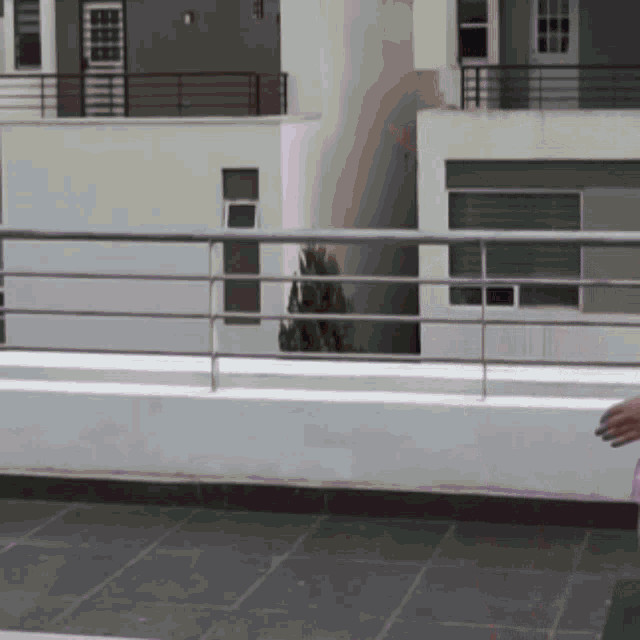 a person standing on a balcony with a metal railing in front of a building