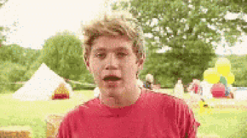 a young man in a red shirt is making a funny face .