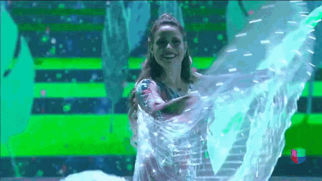 a woman is dancing in front of a green and blue backdrop
