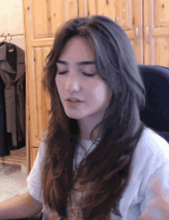 a woman with long hair sitting in a chair with her eyes closed