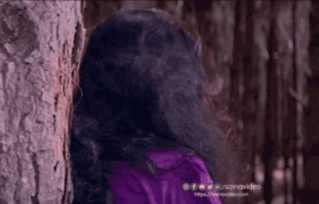 a woman leaning against a tree with the url https://sainavideo.com on the bottom