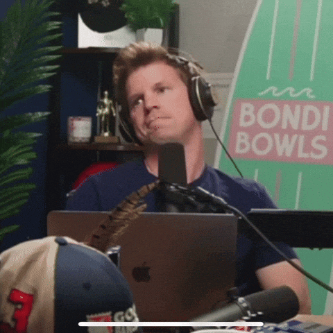 a man wearing headphones sitting in front of a microphone in front of a sign that says bondi bowls