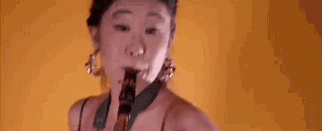 a woman is playing a clarinet in front of a yellow wall .