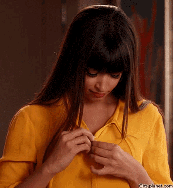 a woman in a yellow shirt is looking at her breast