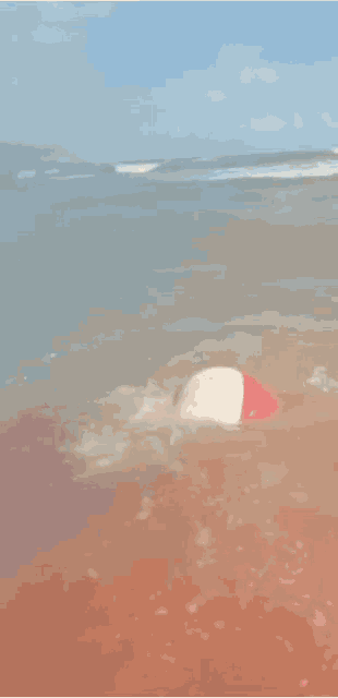 a man is crawling out of the ocean on a beach