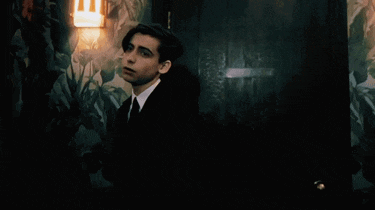 a young man in a suit and tie is standing in front of a door in a dark room .