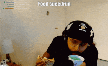 a man wearing headphones and a new york hat is eating a sandwich