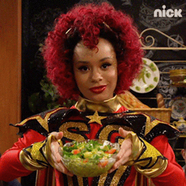 a woman with red hair is holding a bowl of vegetables in her hands