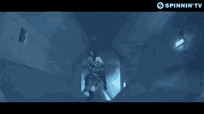 a man is flying through the air in a dark room with a light on the ceiling .