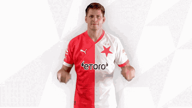 a man is holding up a red and white jersey that says etoro on it