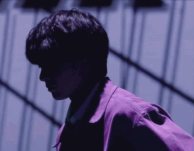 a man in a purple jacket stands in front of a building