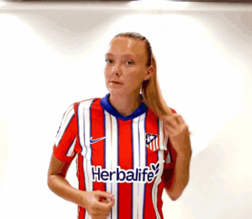 a woman wearing a red and white striped shirt that says herbalife on it