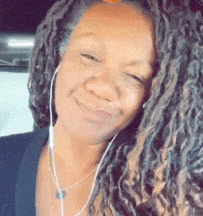 a woman with dreadlocks is wearing headphones and a necklace and smiling .