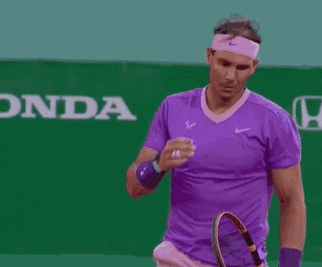a man wearing a headband and a purple shirt is covering his face