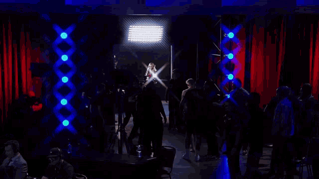 a woman stands in a dark room surrounded by blue lights