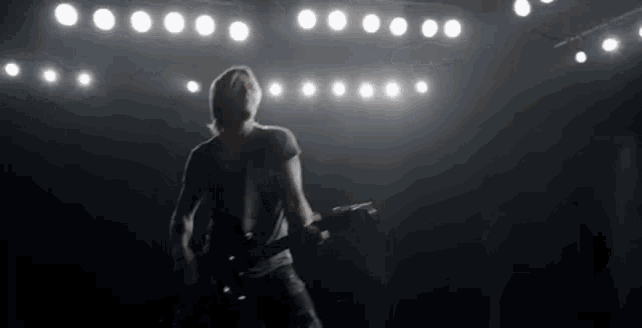 a man is playing a guitar on a stage in the dark .