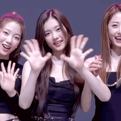 three girls are standing next to each other waving their hands in the air .