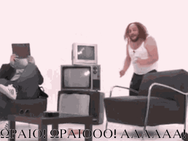 a man in a white tank top is standing in front of a stack of old tvs