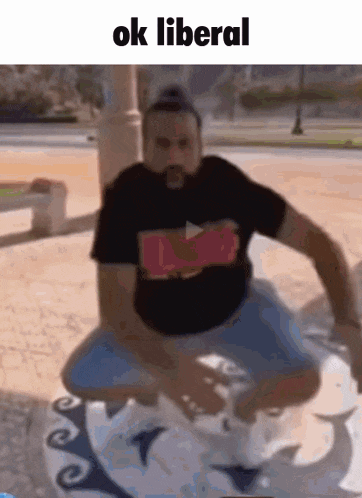 a man in a black shirt is squatting down with the words ok liberal above him