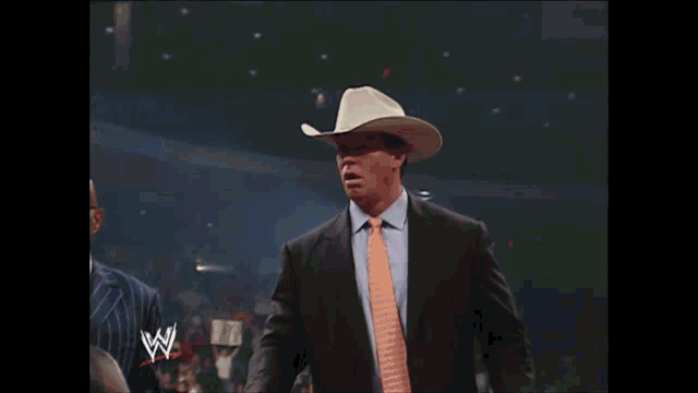 a man in a suit and tie is wearing a cowboy hat with a w logo in the corner
