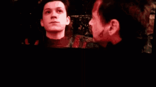 two men are looking at each other in a dark room and one of them has blood on his face .