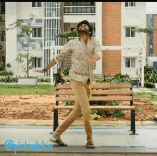 a man is dancing in front of a bench with the hashtag @pichwkka on the bottom right