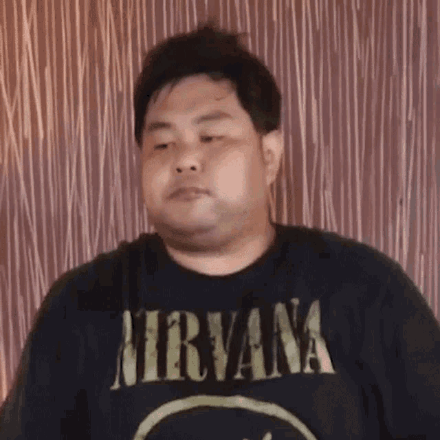 a man wearing a black nirvana t-shirt looks at the camera