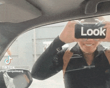 a woman is taking a picture of herself with a phone that says look on it
