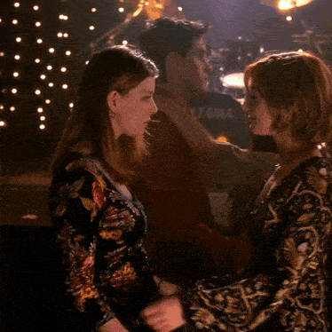 two women are hugging in front of a drum set with the word tama on it