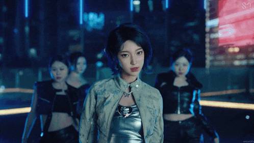 a woman in a silver top stands in front of a group of women