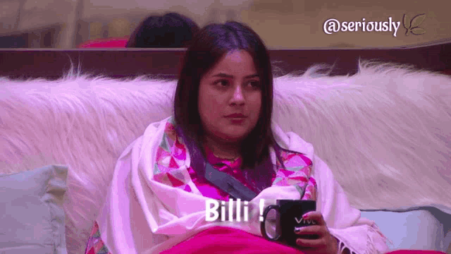 a woman wrapped in a blanket is sitting on a couch holding a mug and says billi !