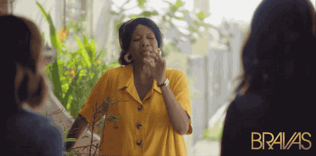 a woman in a yellow shirt with the word bravas on the bottom right