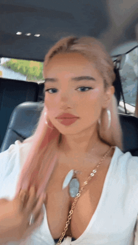 a woman with pink hair is taking a selfie in a car