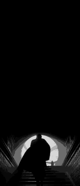 a black and white photo of a man walking down stairs in the dark .