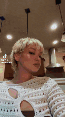 a woman in a white sweater is standing in a kitchen .