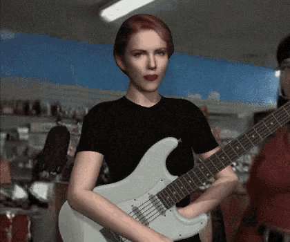 a woman in a black shirt is playing a guitar