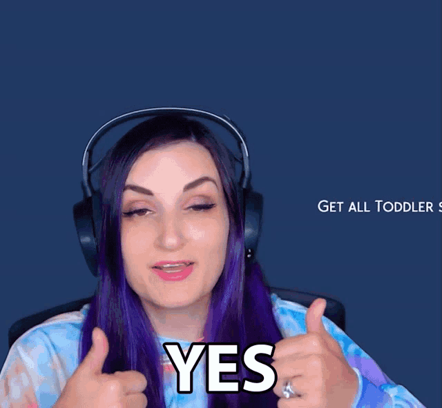 a woman with purple hair wearing headphones giving a thumbs up and saying yes