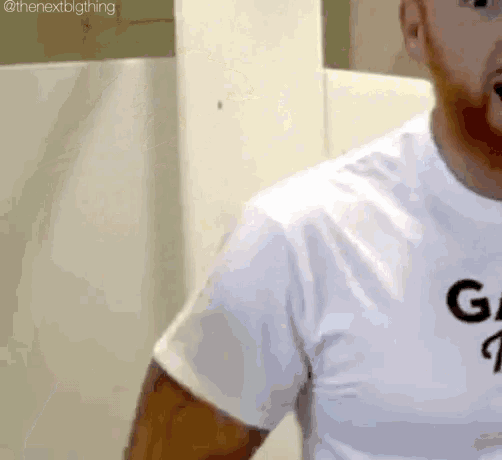 a man is wearing a white t-shirt with a black letter g on it .