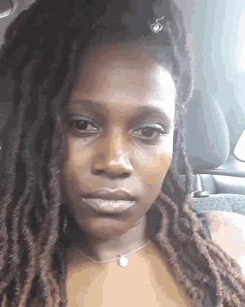 a woman with dreadlocks is sitting in a car and looking at the camera