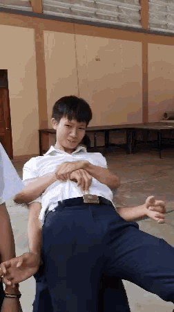 a boy in a white shirt and black pants is being lifted by another boy