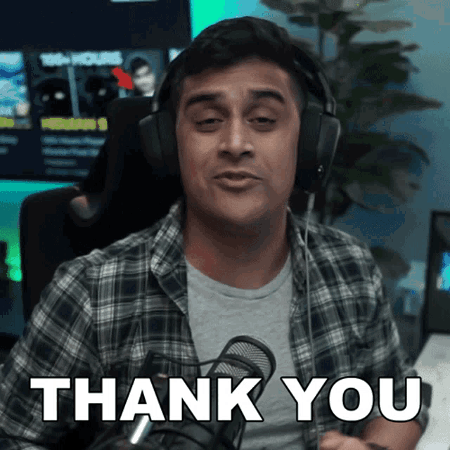 a man wearing headphones says " thank you " in front of a microphone