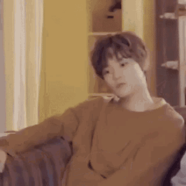a young man is sitting on a couch and looking at the camera .