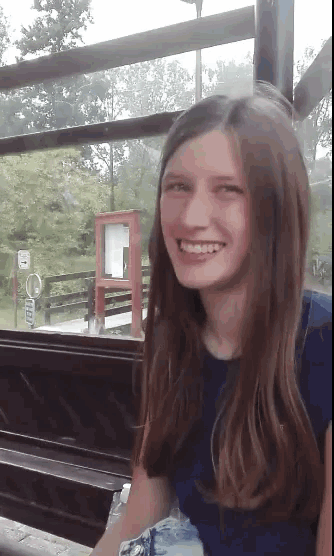 a young girl is smiling in front of a sign that says no smoking